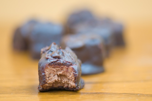 A vegan 3 musketeers bar sits on a wooden counter with more candies behind it.