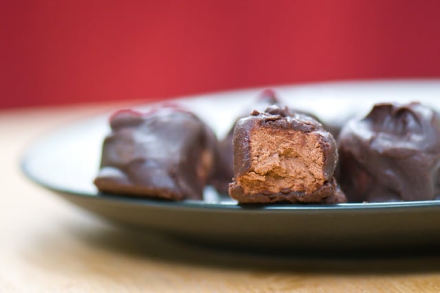 A vegan 3 muskateers with a bite taken out sits on a plate next to other pieces of the candy.