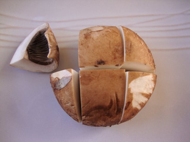 Looking down on a portobello mushroom chopped into 6 pieces.