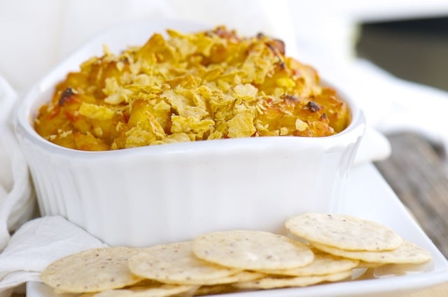 Vegan dip in a white bowl with a white background and crackers in front for dipping.