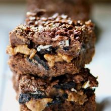 A stack of brownies shoes peanut butter, Oreo chunks, and a chocolate topping.