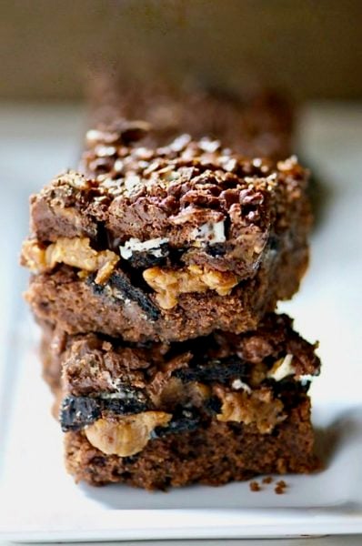 A stack of brownies shoes peanut butter, Oreo chunks, and a chocolate topping.