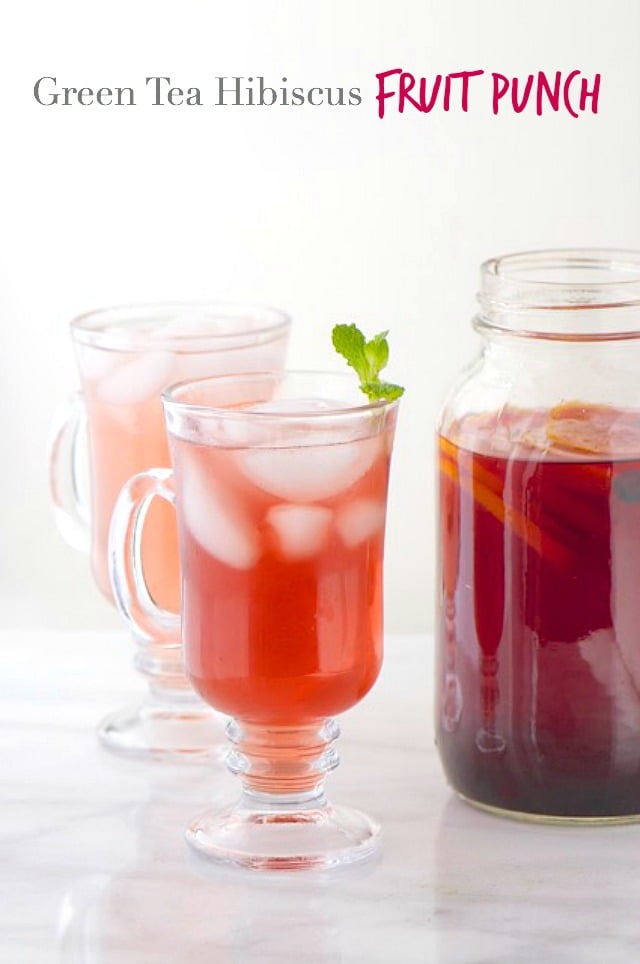Two tall glasses with ice and punch inside, one with a mint sprig at the top are sitting next to a mason jar full of punch. The text at the top reads, "Green Tea Hibiscus Fruit Punch."