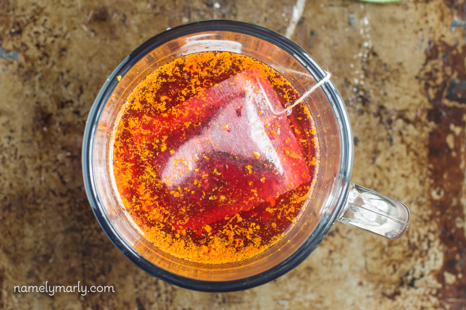Looking down on a tea bag in a cup of water with a little bit of orange zest added