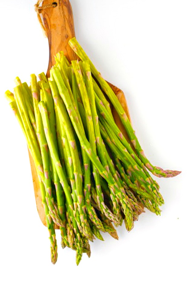 Looking down on a cutting board full of asparagus.