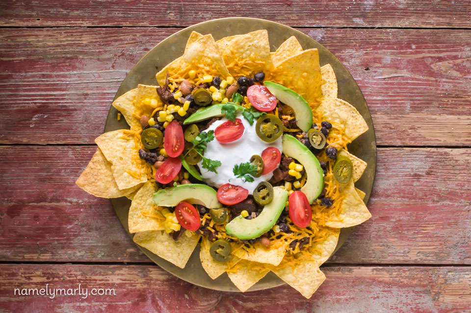 Looking down on a serving platter full of nachos topped with bulgogi jackfruit and other toppings.
