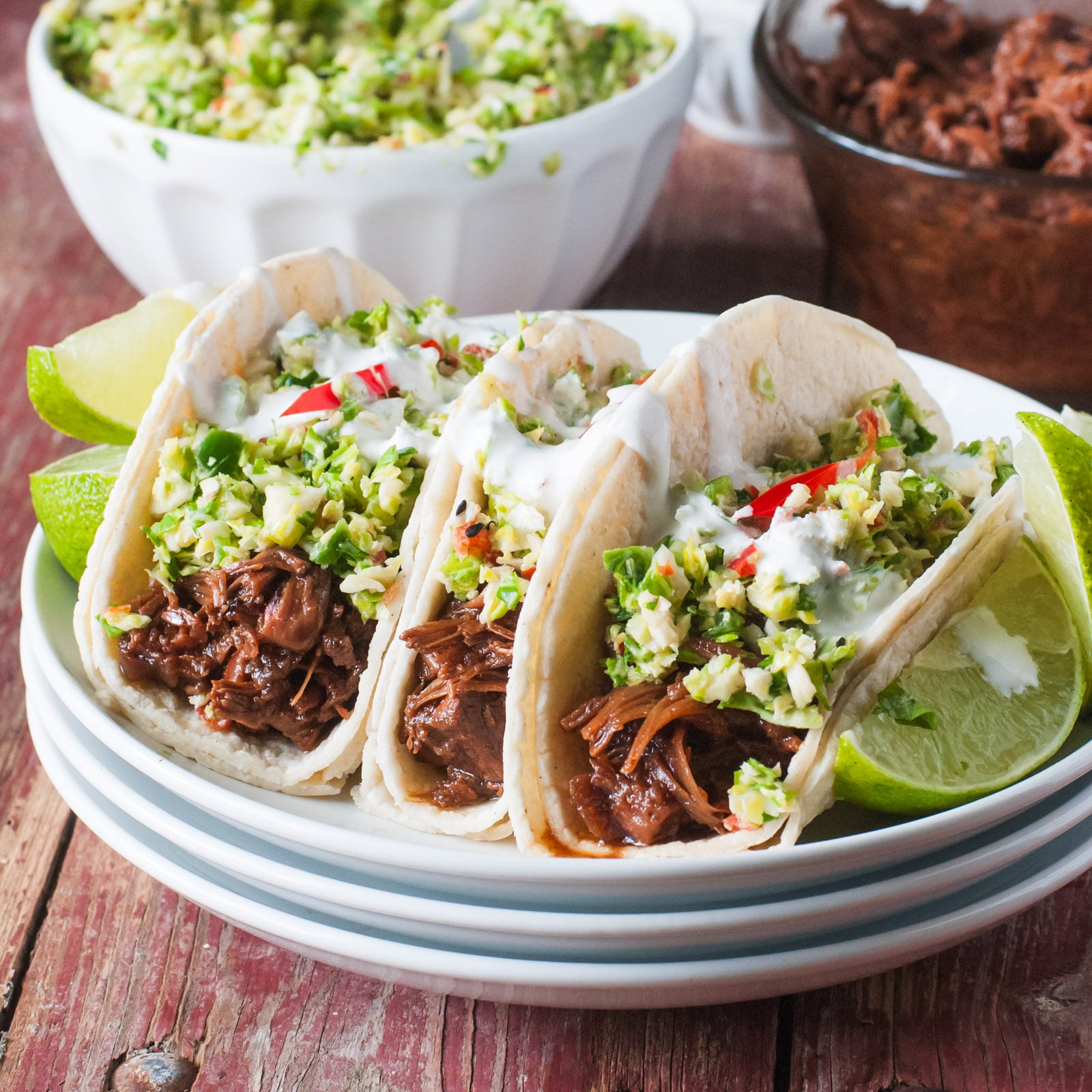 Three Vegan Bulgogi Street Tacos sit in front of a dish o bulgogi jackfruit and slaw.