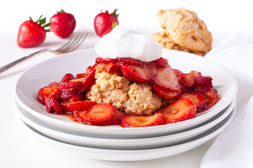 A biscuit is topped with sliced strawberries and whipped cream.