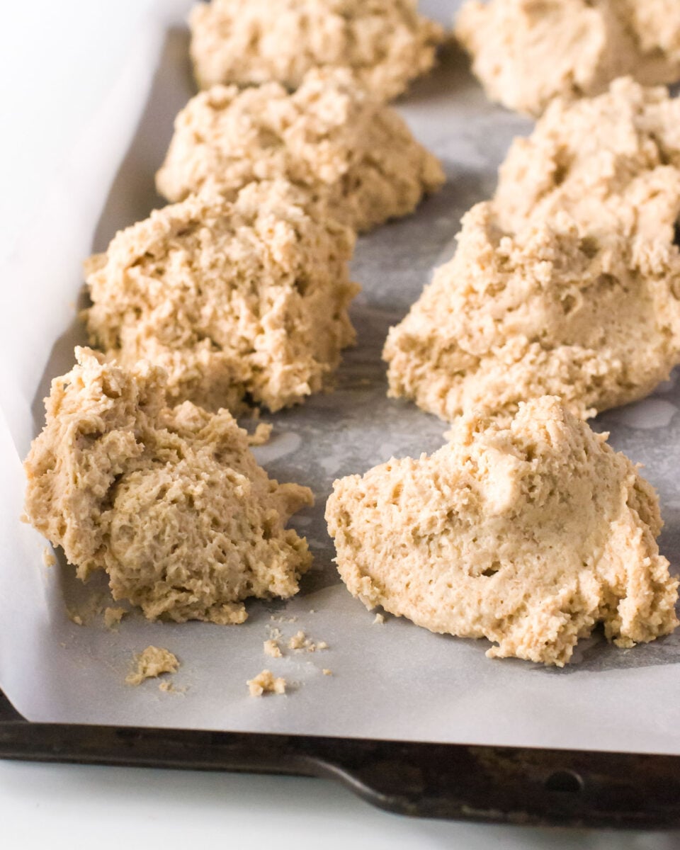 Biscuits have been dropped on a baking sheet and ready to go in the oven.