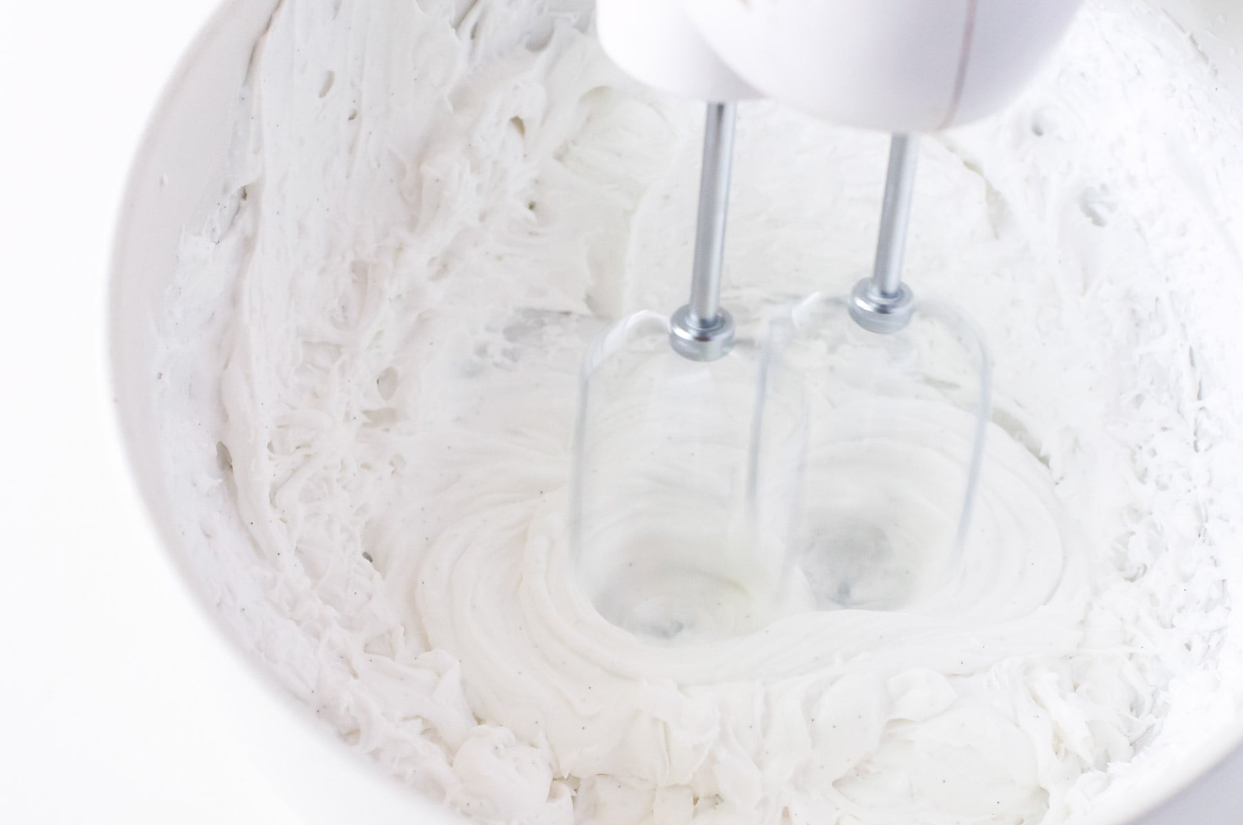 A hand-held mixer is whipping up the chilled coconut fat.