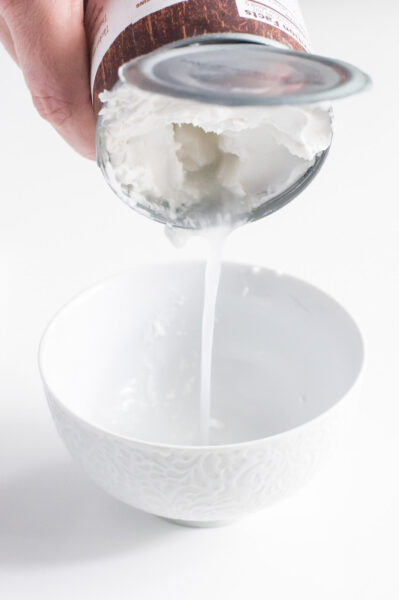 a can of coconut milk being drained into a bowl