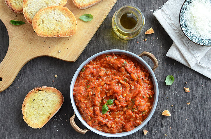 Looking down on a bowl of tomato dipping sauce next to toasted bread slices.