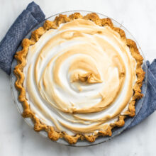 Looking down on a pie sitting on a blue kitchen towel. The meringue has golden edges.