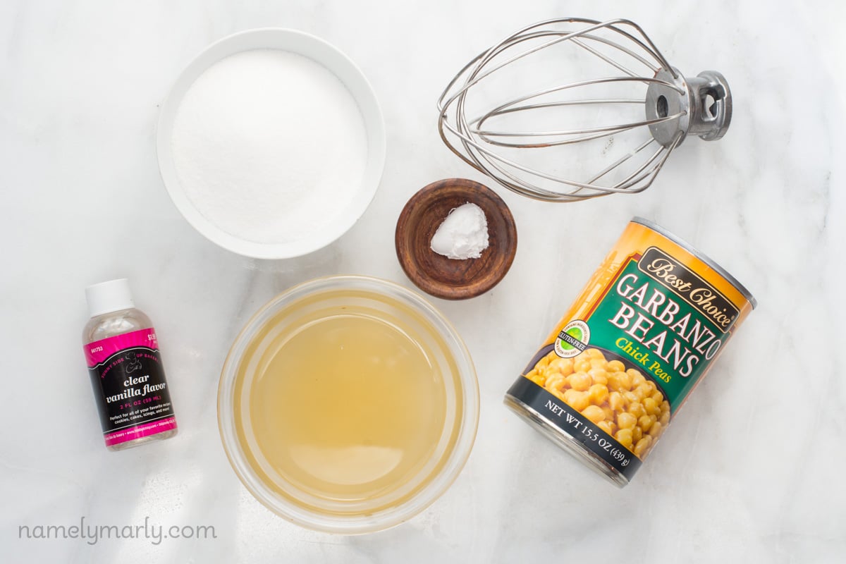 Looking down on ingredients to make vegan meringue, including a can of chickpeas, and sugar in a bowl.