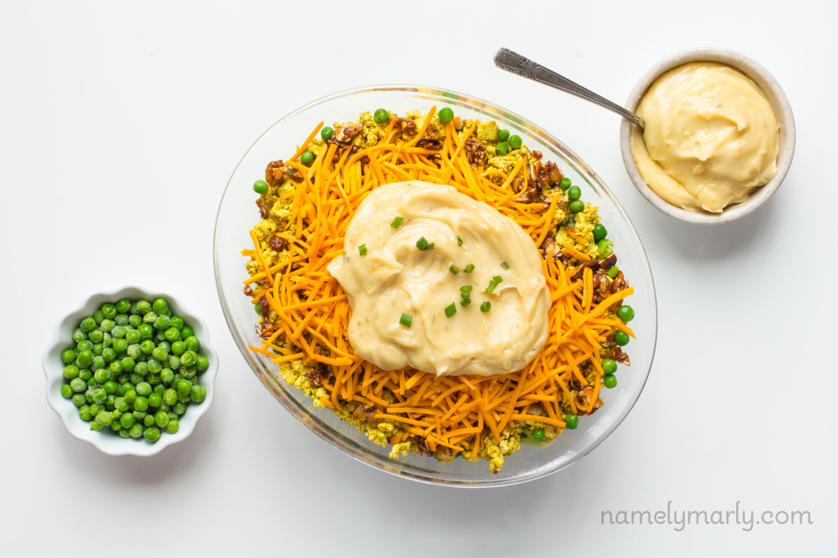 Looking down on three bowls, one with frozen peas, one with vegan ranch, and another with vegan salad.