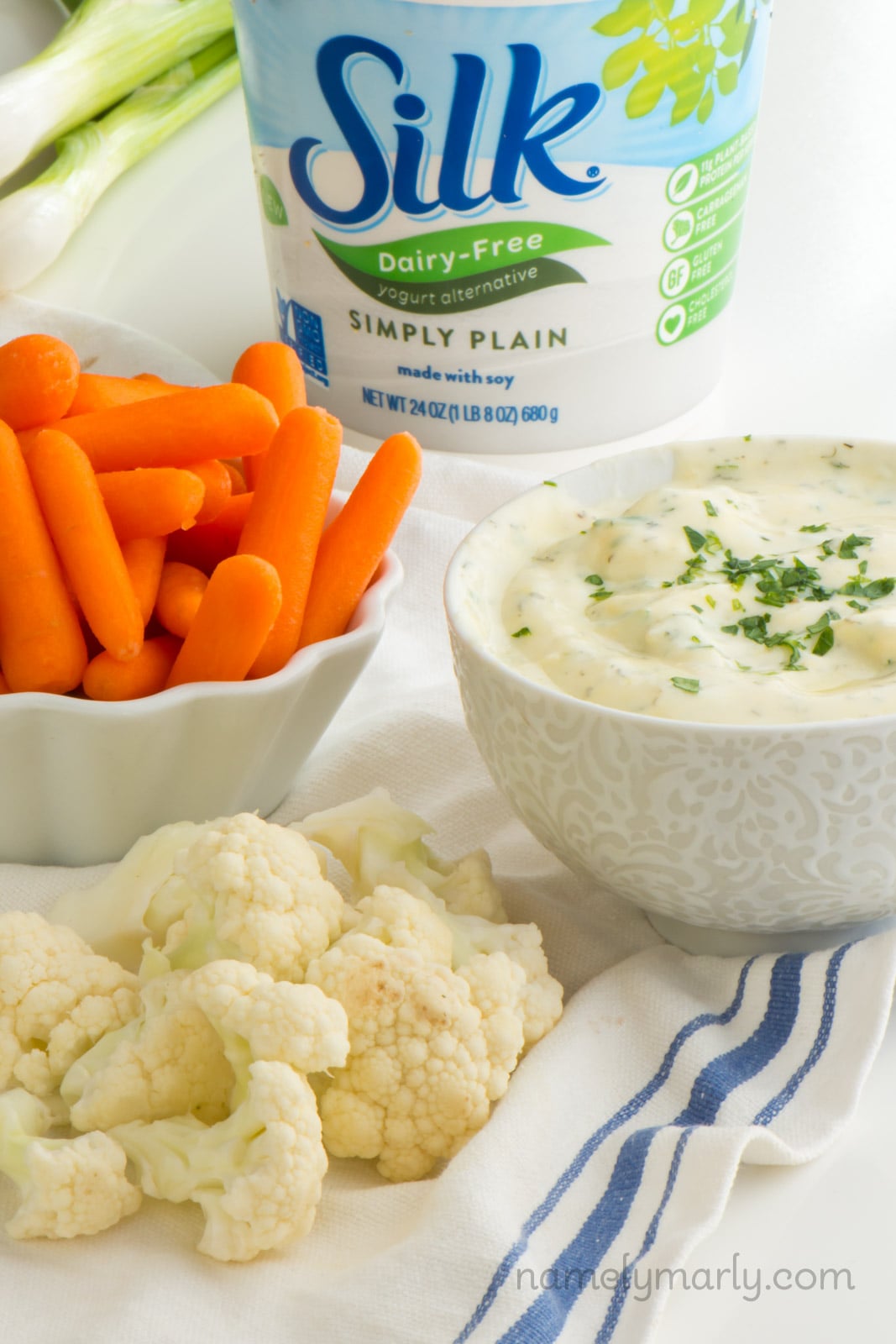 A bowl of ranch dip by cut up veggies and beside vegan yogurt.