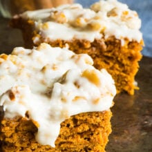 Two slices of vegan pumpkin blondies sit in front of a jar of cinnamon spice.