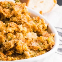 Picture of Vegan Stuffing in a white casserole dish with a loaf of french bread in the background