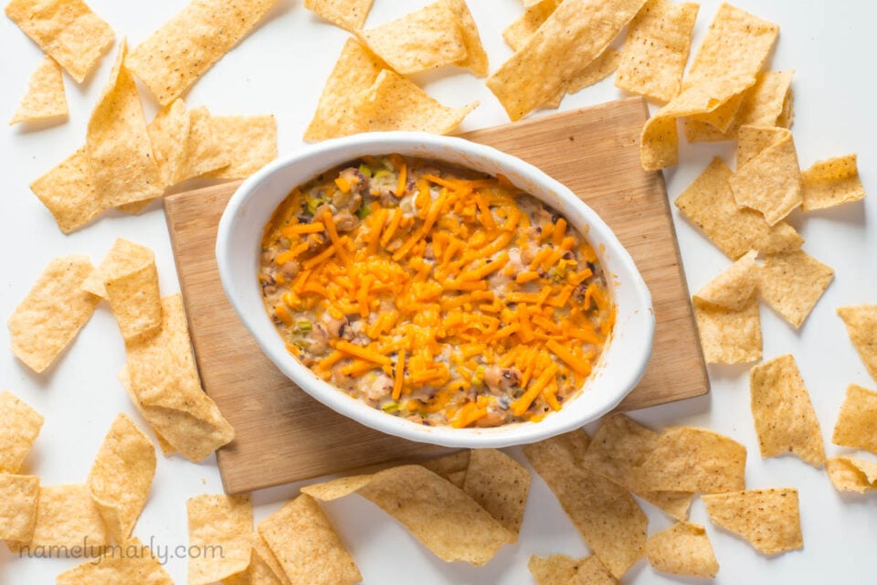 Looking down on a dish full of vegan black-eyed pea dip sitting on a cutting board with tortilla chips around it. 