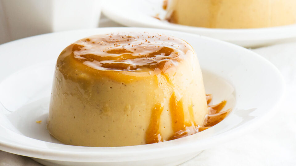 Two plates with vegan flan next to a cup of tea.