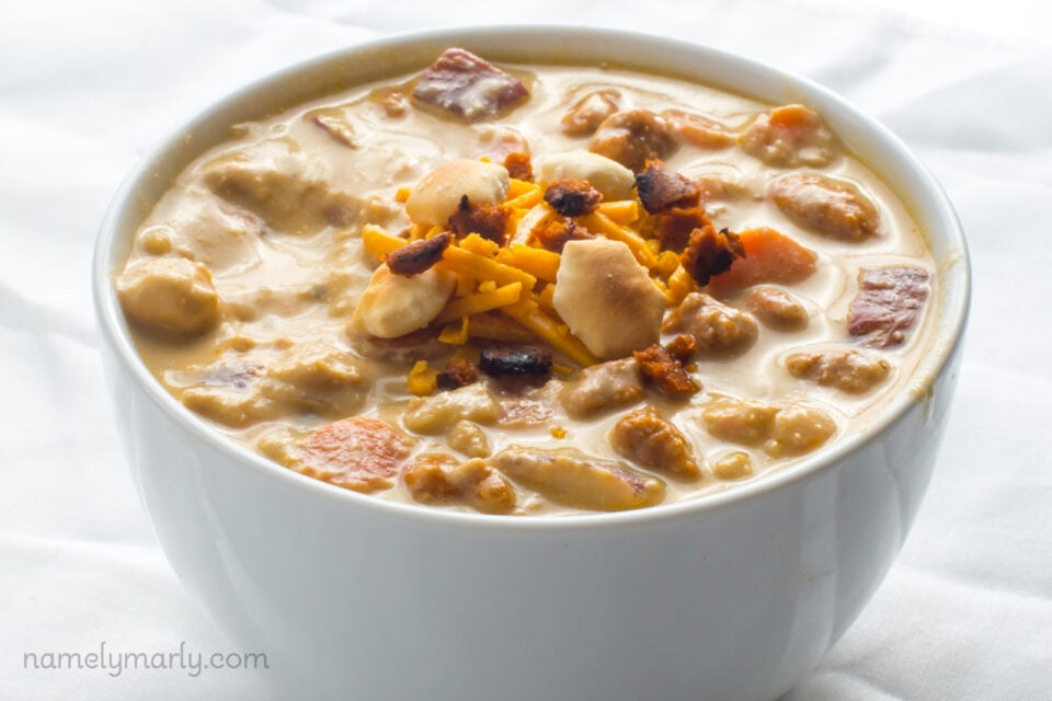 A bowl of vegan cheeseburger soup with vegan cheddar shreds and crackers on top.