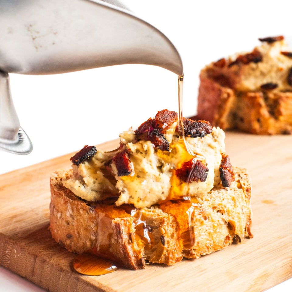 Drizzling maple syrup over a slice of vegan ricotta crostini.