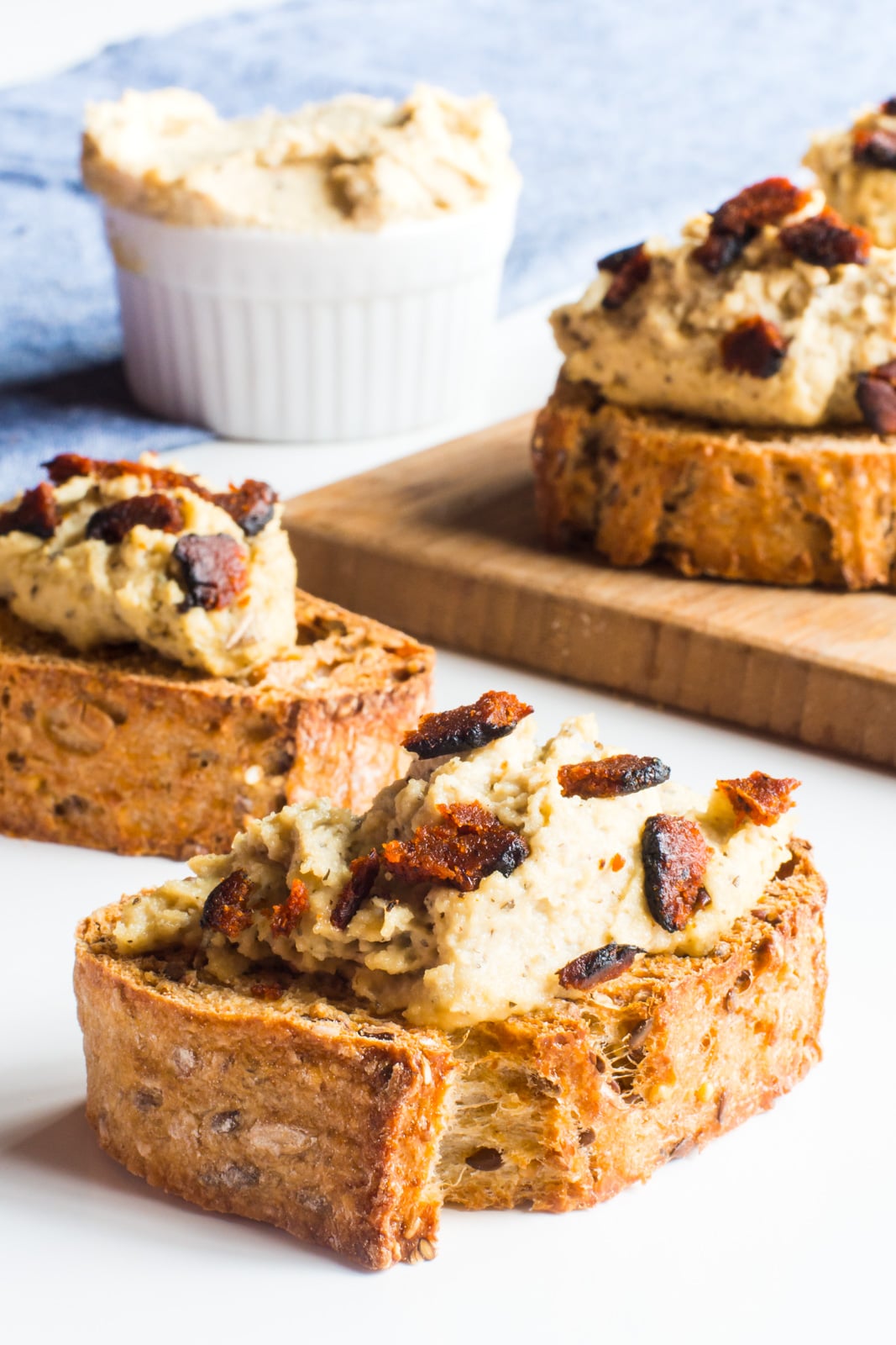 A closeup of crostini with vegan ricotta on top and vegan bacon crumbles.