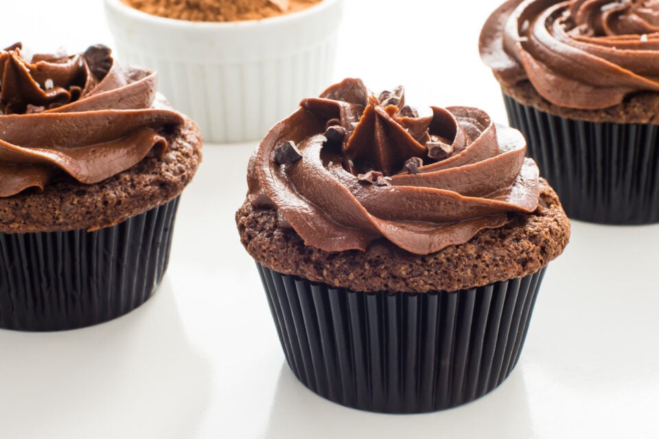 Several vegan chocolate stout cupcakes sitting next to each other on a white table.