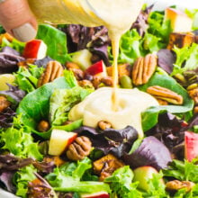 Pouring a jar of pumpkin ranch dressing over a vegan harvest salad.