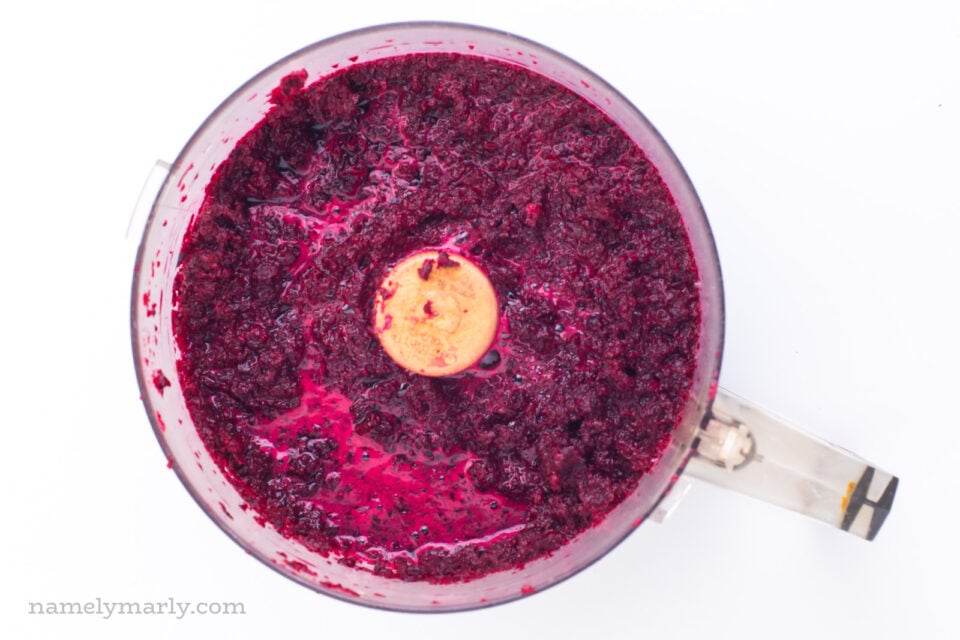 Looking down on a food processor full of bright pink ingredients.