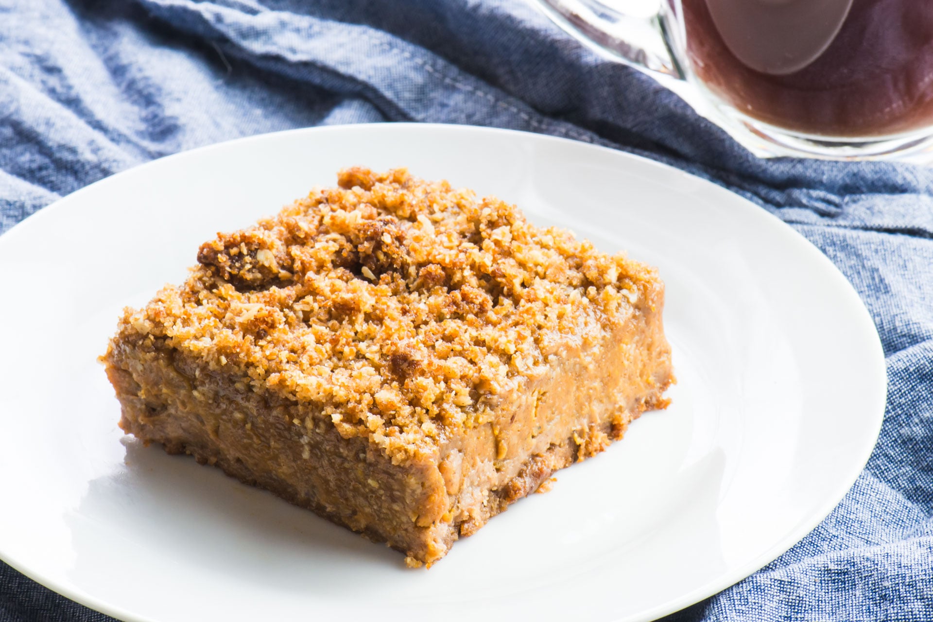 A pumpkin pie bar on a white plate with a blue cloth napkin behind it.