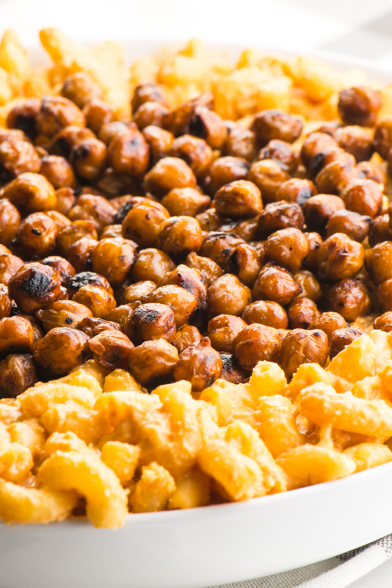 Looking a smoky roasted chickpeas in a bowl surrounded by vegan mac and cheese.