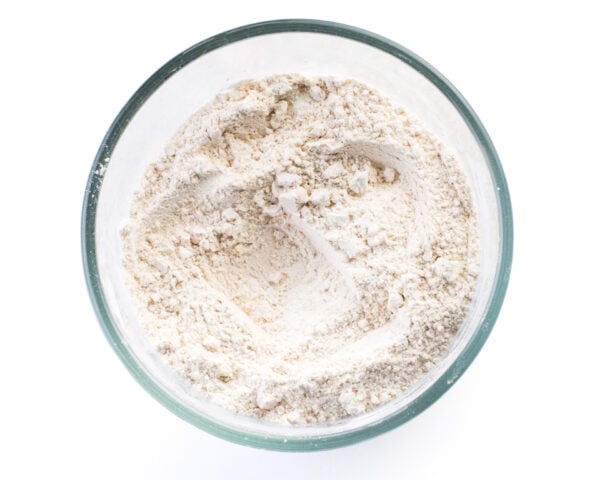 Dry ingredients, like flour, in a glass bowl.