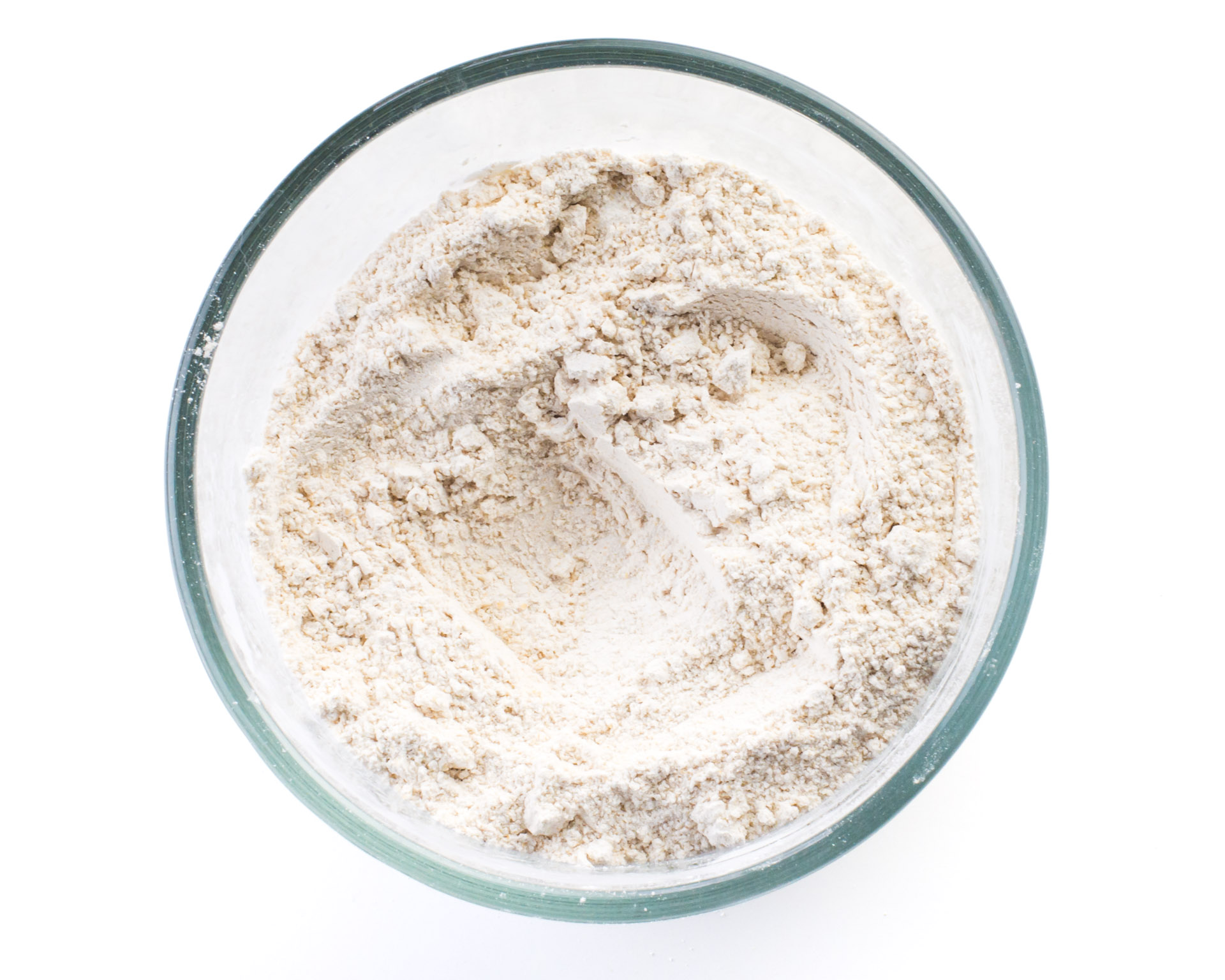 Dry ingredients, like flour, in a glass bowl.