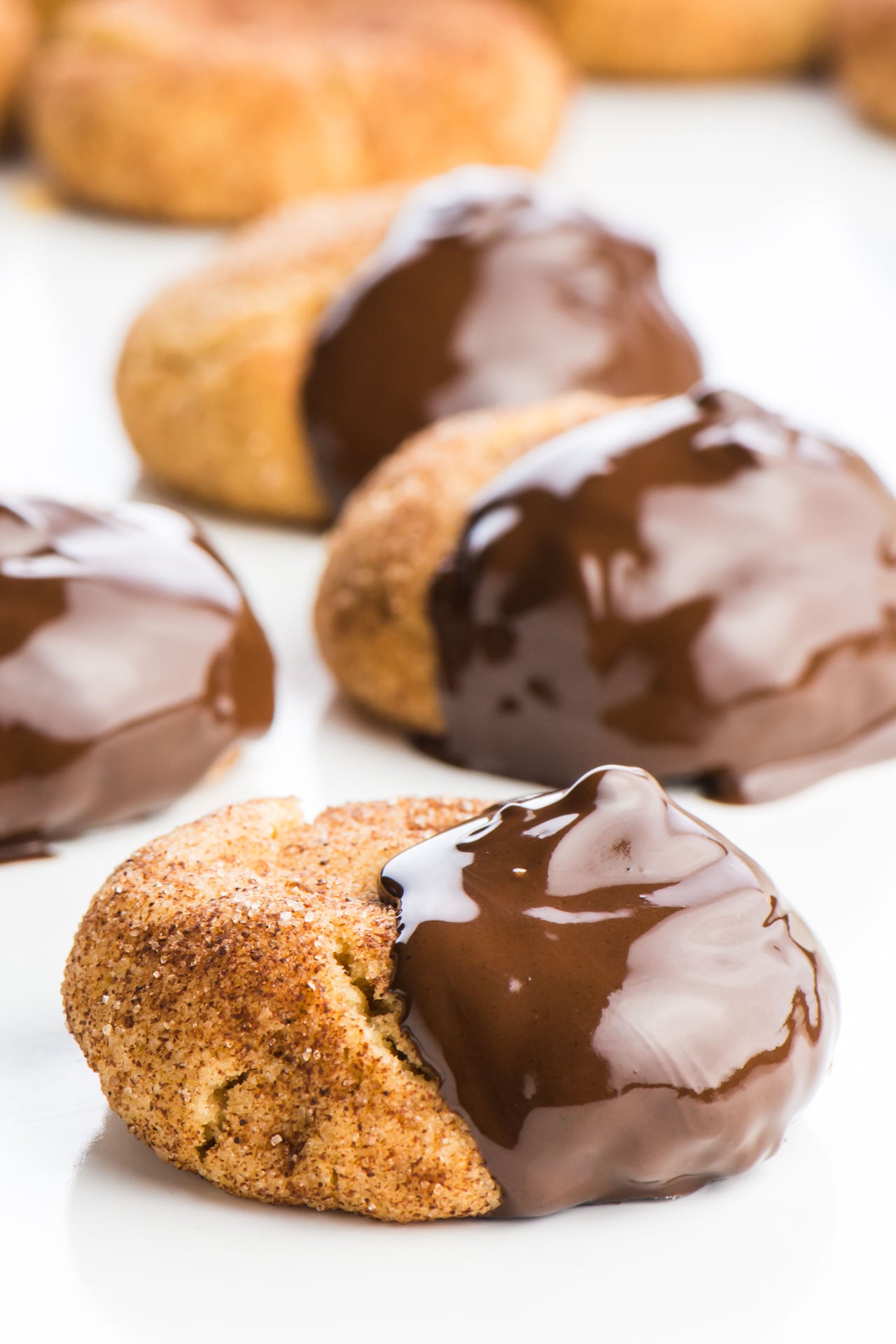 Several chocolate-dipped snickerdoodle Cookes are on a white countertop.