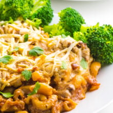 Vegan Macaroni Casserole is on a white plate with stated broccoli in the background.