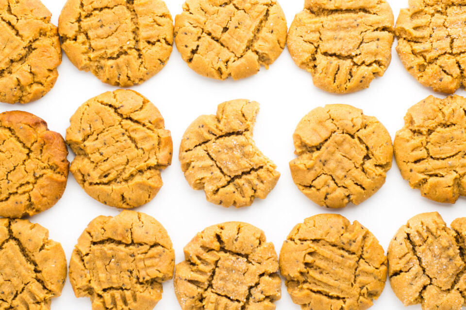 Rows of finished vegan cookies sit next to each other. There's a bite taken out of the one in the middle.
