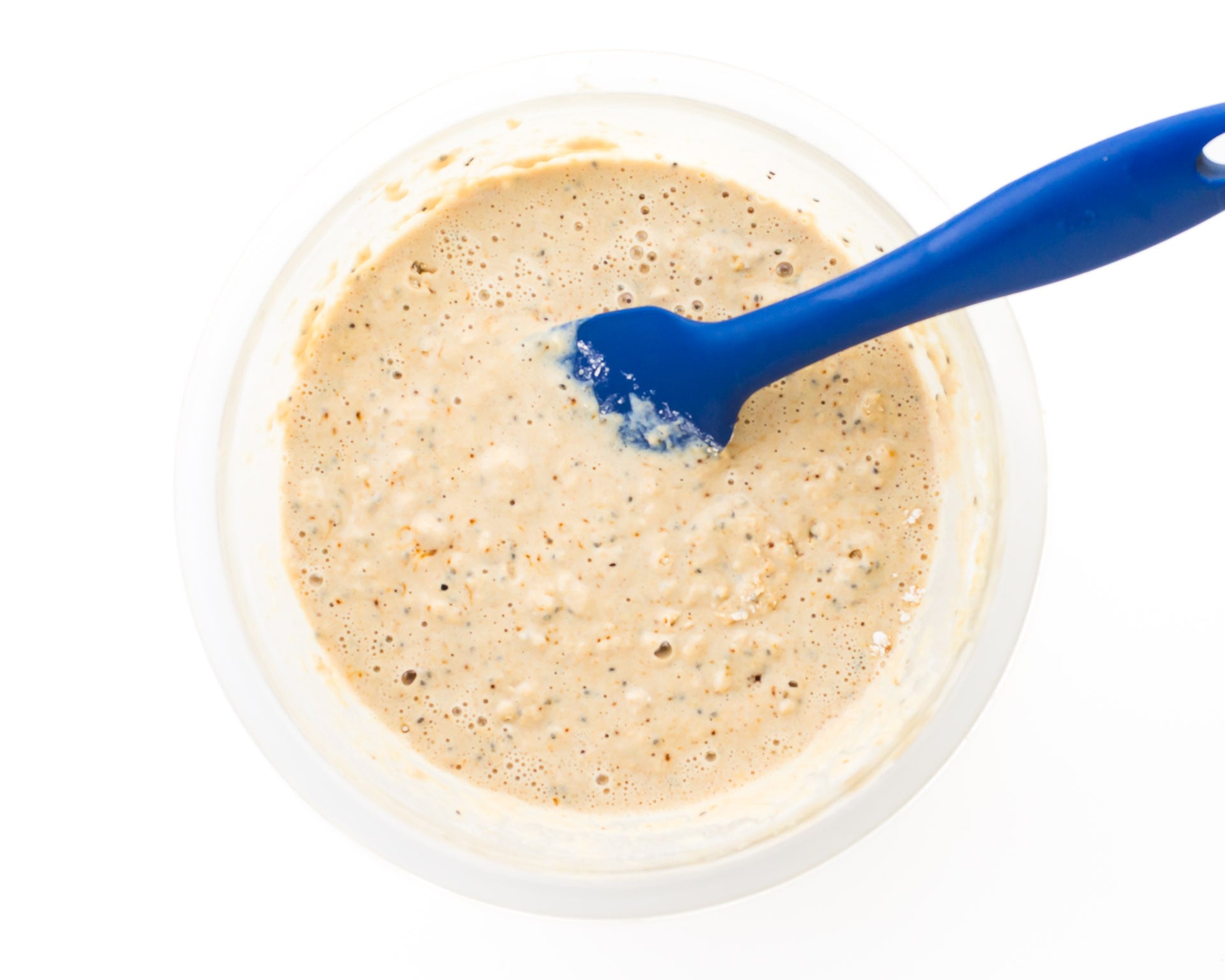 Batter in a glass bowl with a blue spatula.