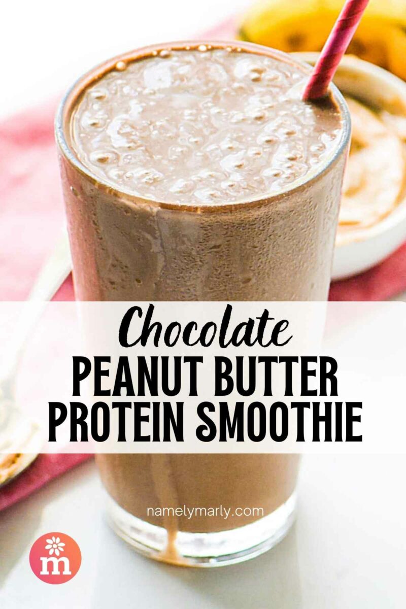 Chocolate peanut butter protein smoothie in a tall glass with a pink straw.