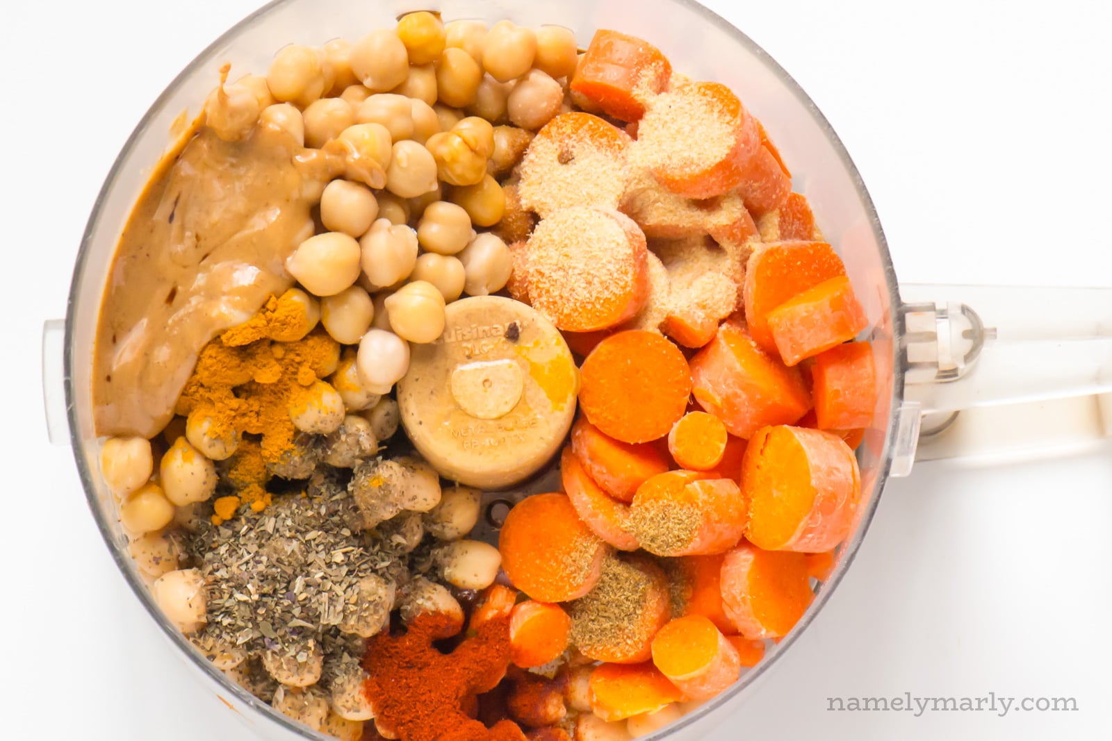 The ingredients for carrot hummus in a food processor bowl.