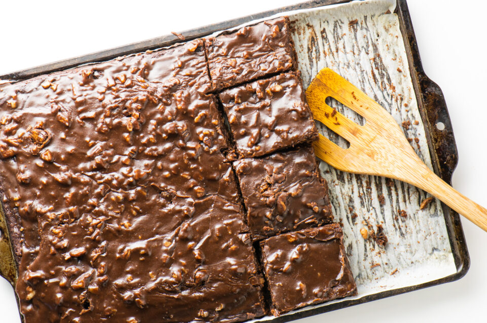 Looking down on a baking dish full of Texas sheet cake, with a spatula ready to remove a slice.