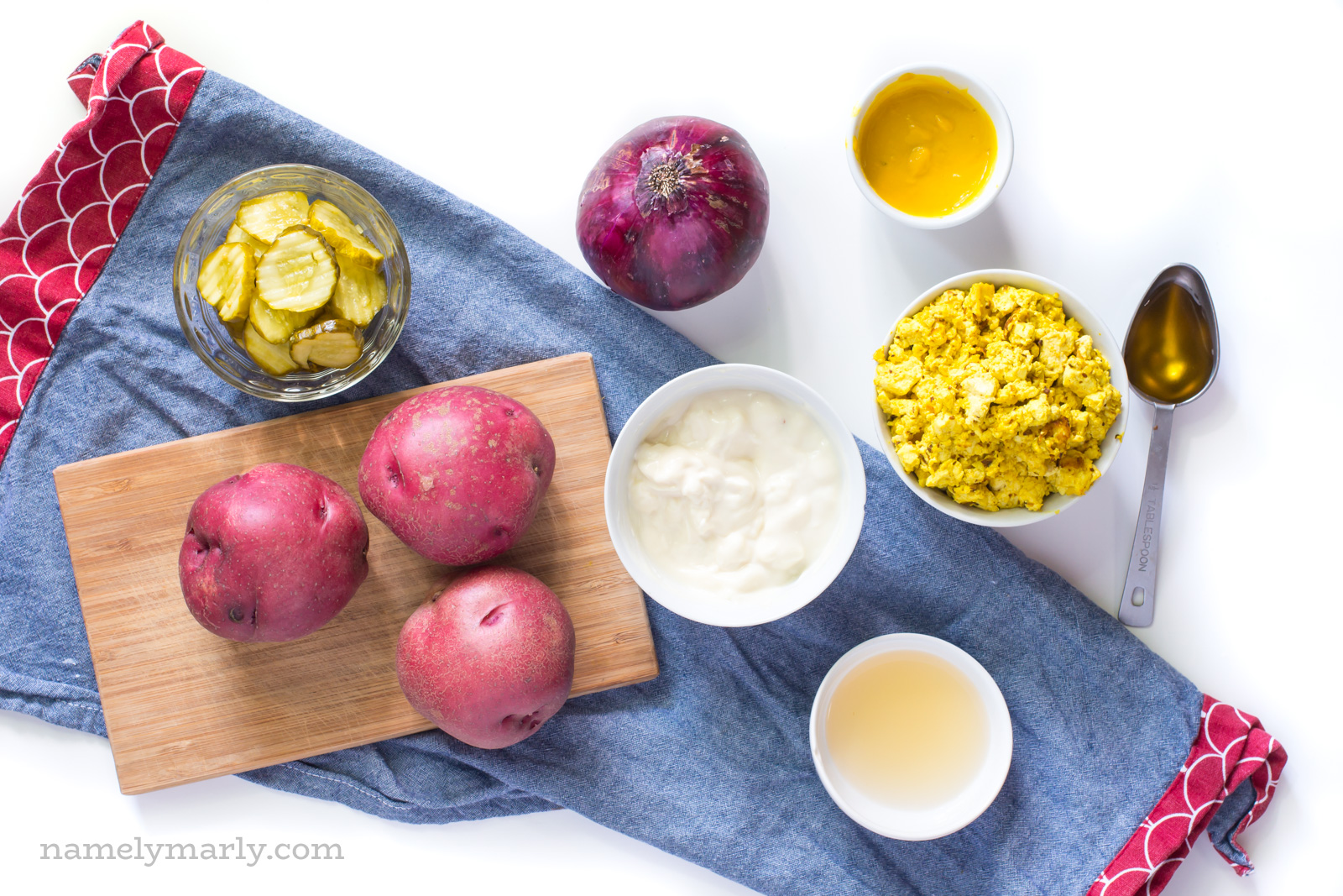 Ingredients on a blue kitchen towel, including red potatoes, pickles, tofu scramble, onions, and more.