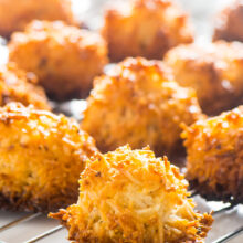 Several gluten free macaroons sit on a wire rack, cooling after being baked.