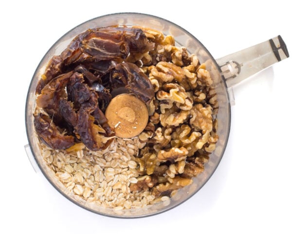 Oatmeal, dates, and walnuts in a food processor bowl.