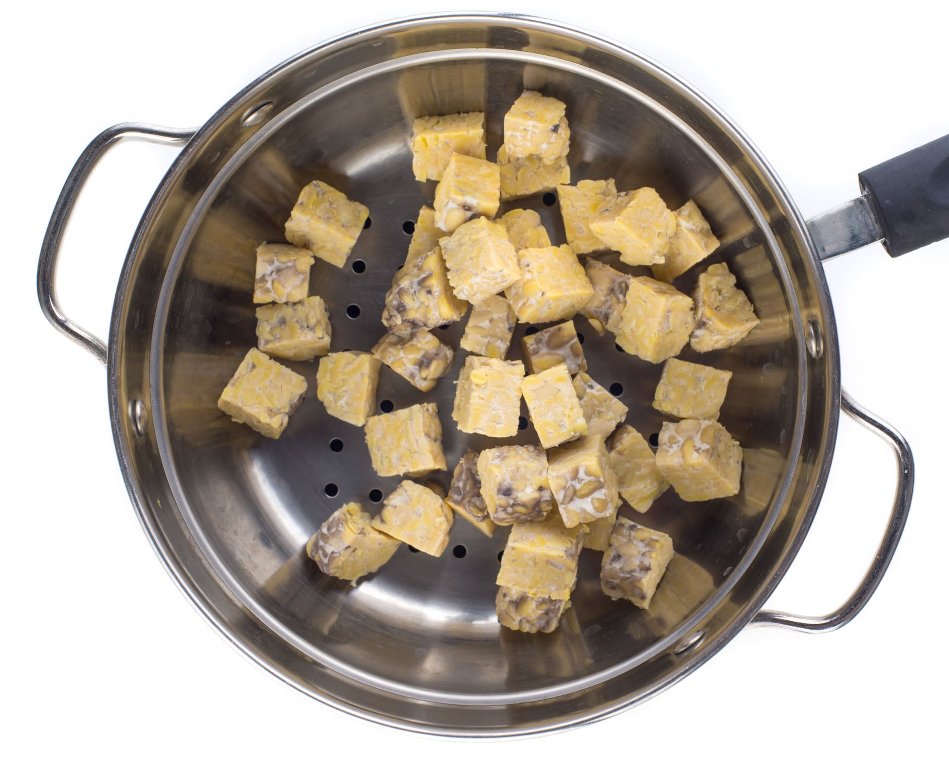 Tempeh cubes in a steaming basket.