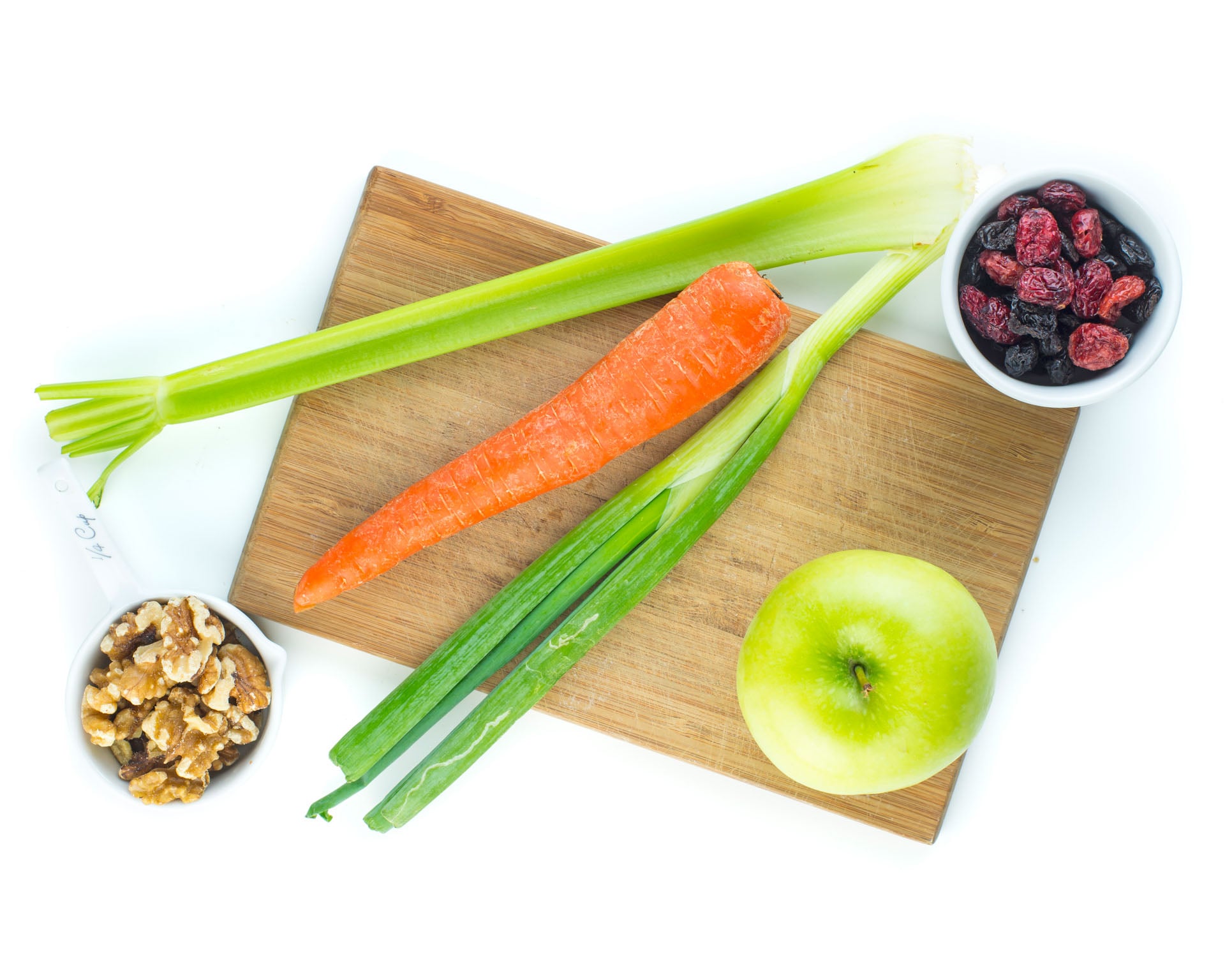 Other ingredients for this vegan chicken salad, like celery and green onions, sit on a cutting board.