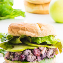 A vegan chicken salad sandwich sits in the foreground with ingredients behind it.