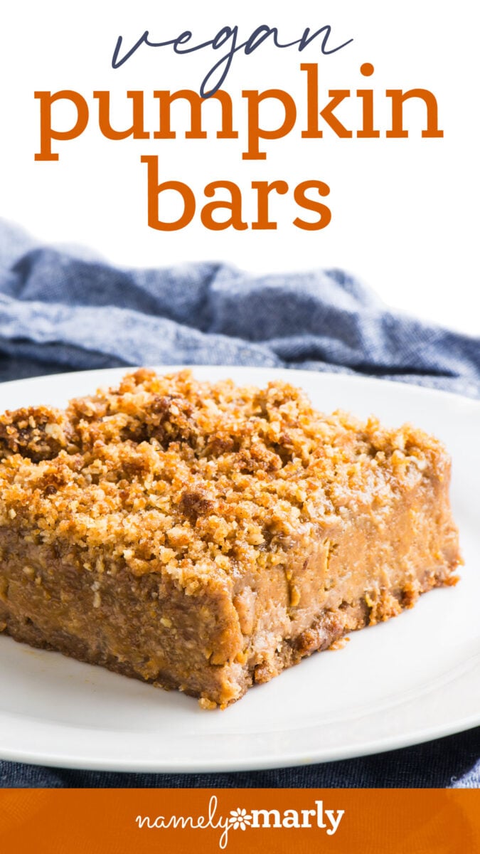 Vegan pumpkin bars with a crumbly topping, served on a white plate with a blue cloth in the background.