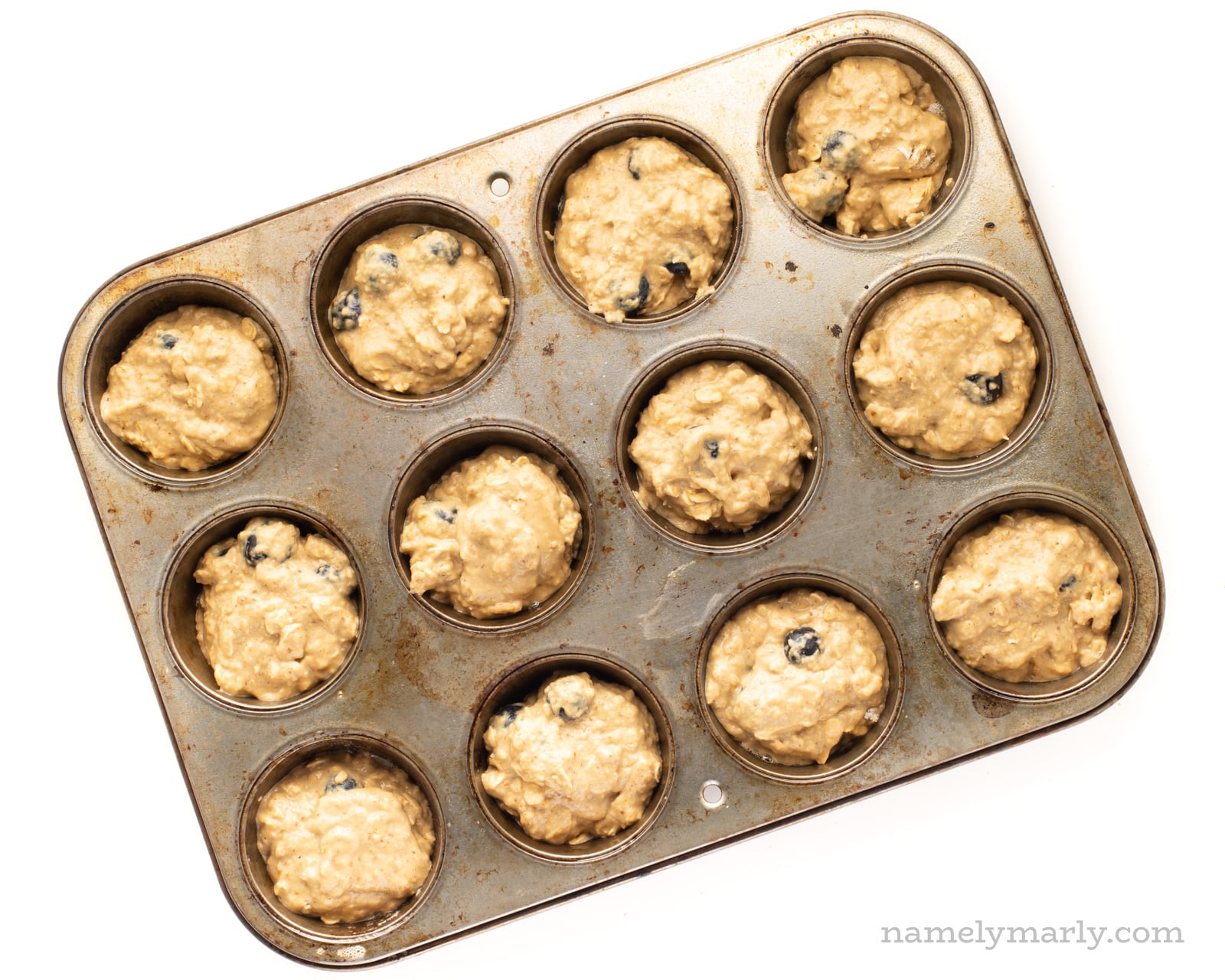 Vegan muffin dough in a muffin pan ready to go in the oven.