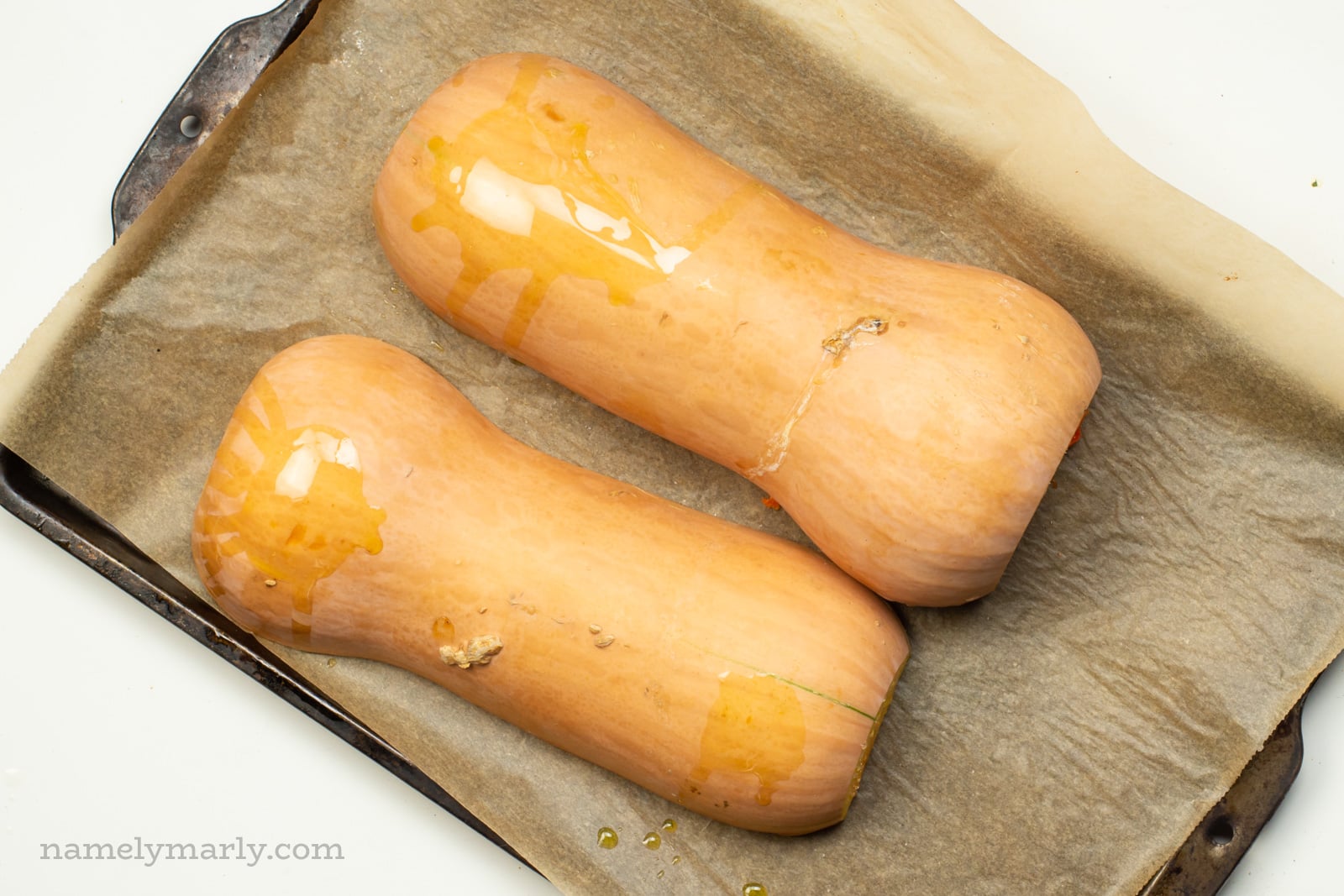 Butternut squash are placed cut side down on a baking sheet.